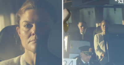 Kronprinsessan Victoria sitter med allvarlig min i ett fordon, omgiven av personal