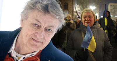 Lars Lerin i porträtt intill en gråtande kvinna som håller en ukrainsk flagga bland demonstranter