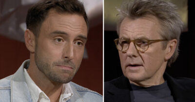 Två män i tv-intervju, en yngre man med allvarlig min och en äldre man med glasögon som talar